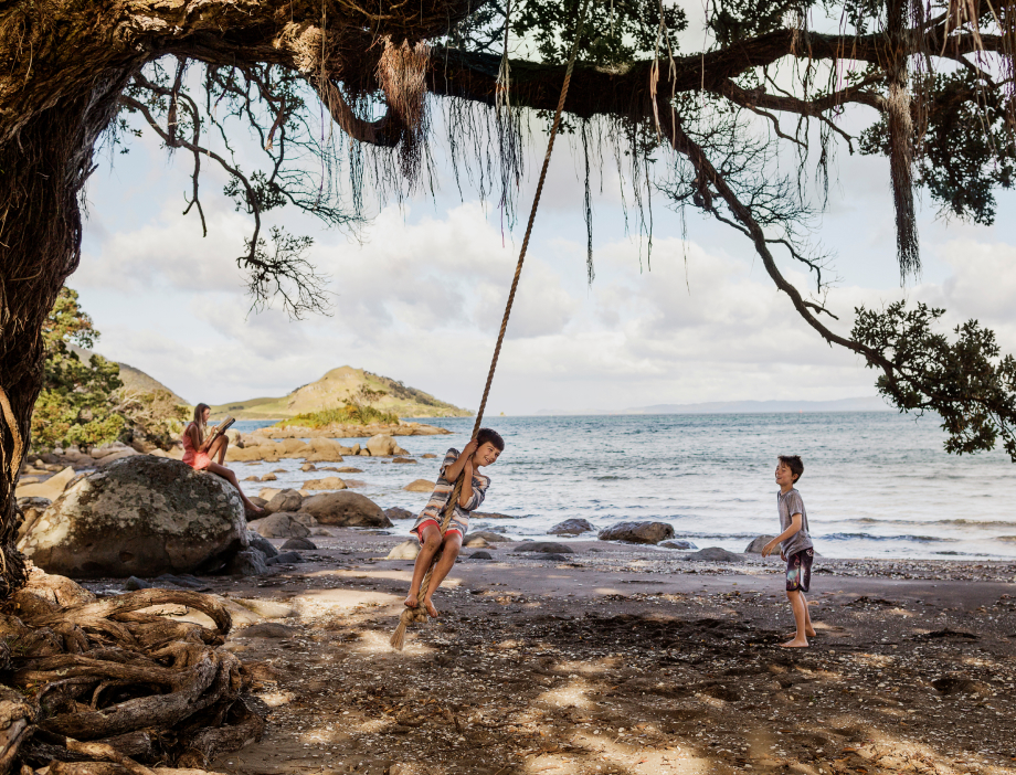 Children playing on a rope swing at the beach.