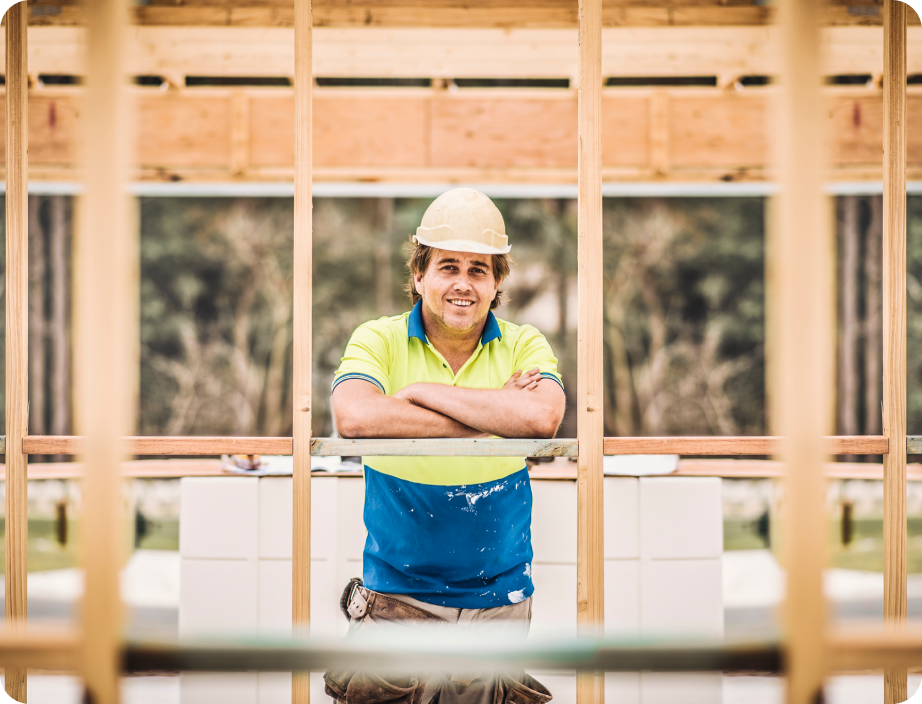 A builder leans against the frame of a building he's constructing.
