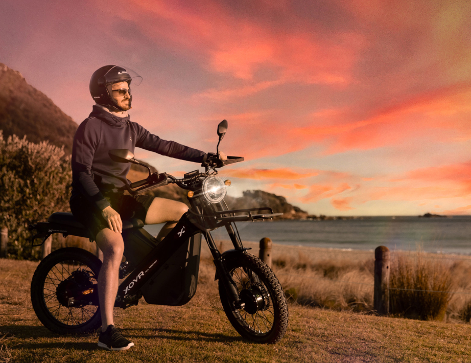 A man on an electric bike parked in front of the ocean.