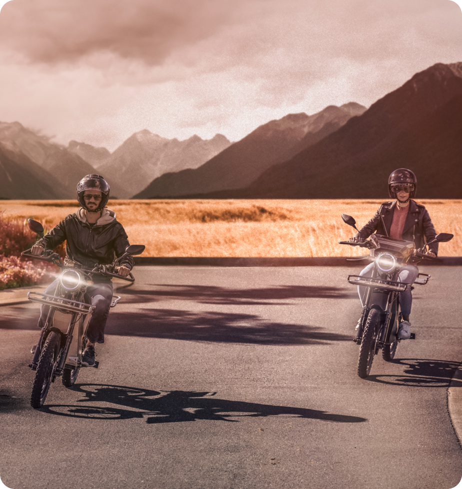 A man and woman ride ebikes on a mountain valley highway.