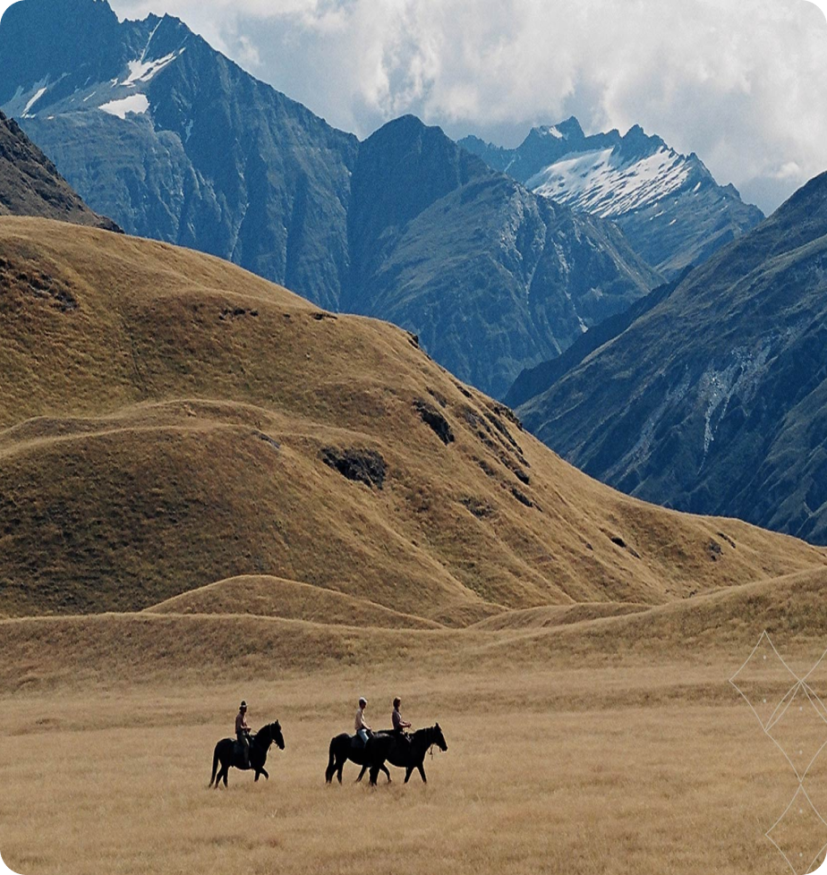 People ride horses through a valley on the South Island of New Zealand.