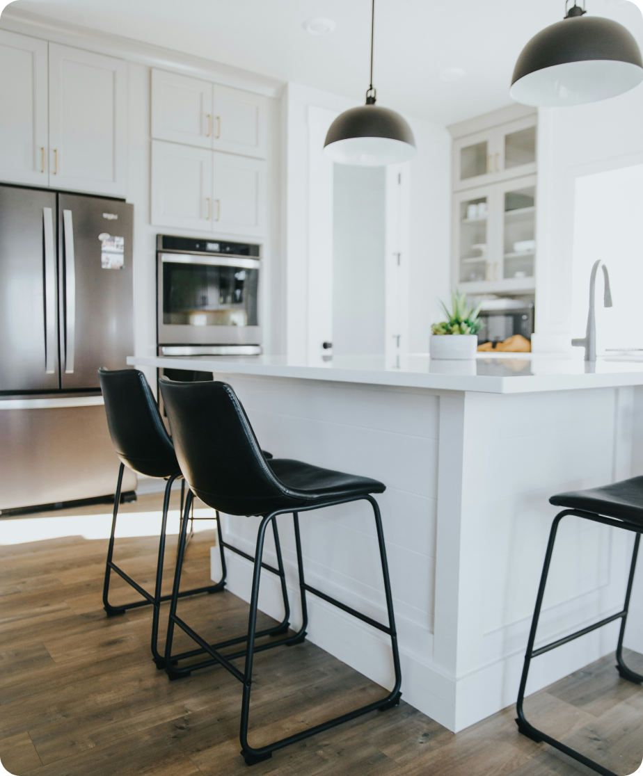 Chairs at an island in a white modern kitchen.