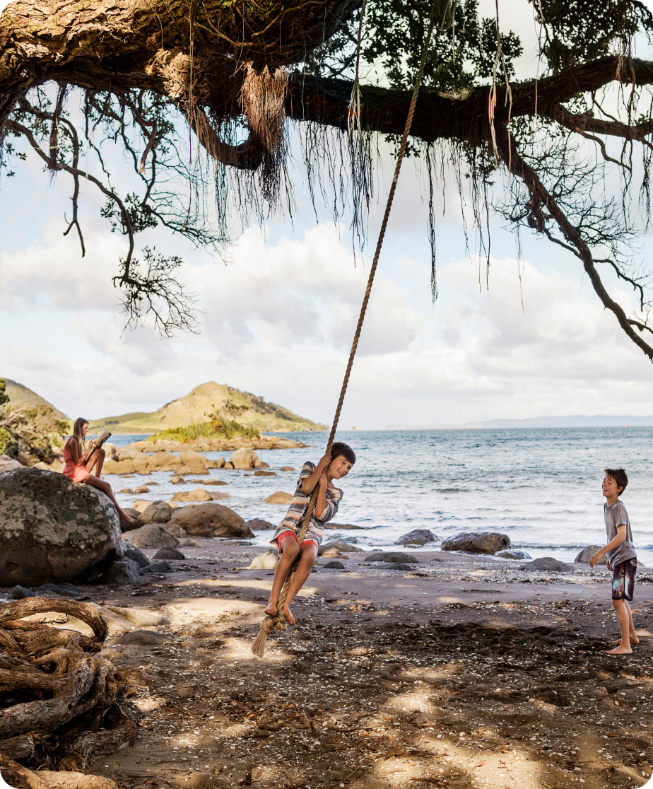 Children playing on a rope swing at the beach.