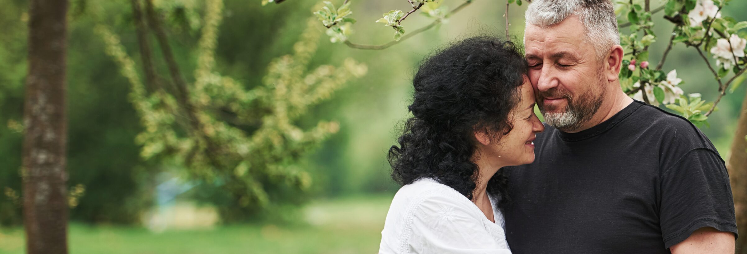 A woman leans her forehead against a man's cheek.